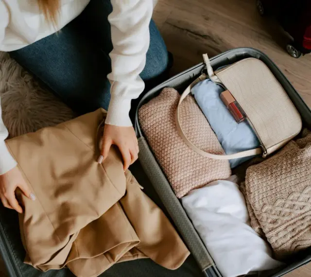 Pakowanie walizki. Zastanawiasz się, ile kosztuje dokupienie bagażu rejestrowanego Ryanair? W środku ubrania, torebka i kosmetyki.