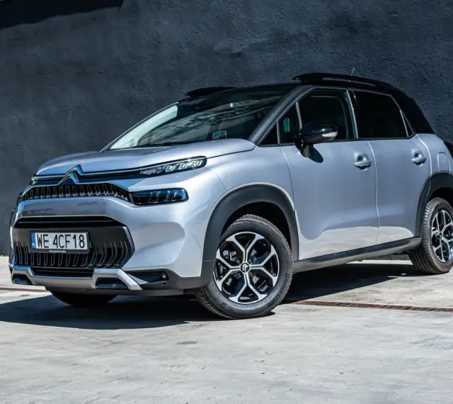 Srebrny Citroen C3 Aircross na tle ciemnej ściany. Wiele osób szuka **Citroen C3 Aircross opinie** przed zakupem.