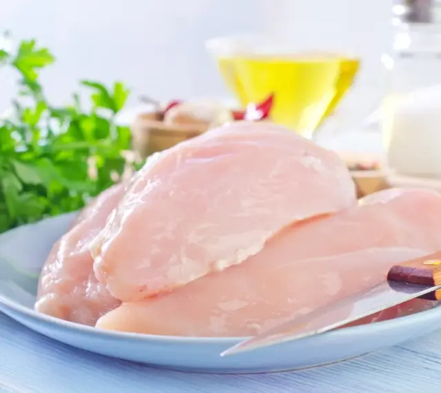 Surowe filety z kurczaka na talerzu, gotowe do przygotowania. W tle olej, sól i natka pietruszki. Idealne dla dbających o filet z kurczaka kcal.