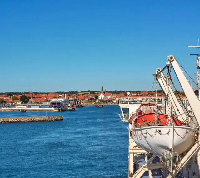 Widok z promu na Bornholm. Widać port, miasteczko z czerwonymi dachami i kościołem, a na pierwszym planie łódź ratunkową.