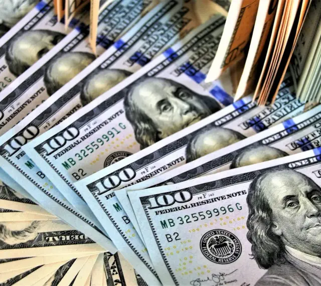 Stos banknotów 100-dolarowych, symbolizujących zabezpieczenie majątkowe w postępowaniu karnym.