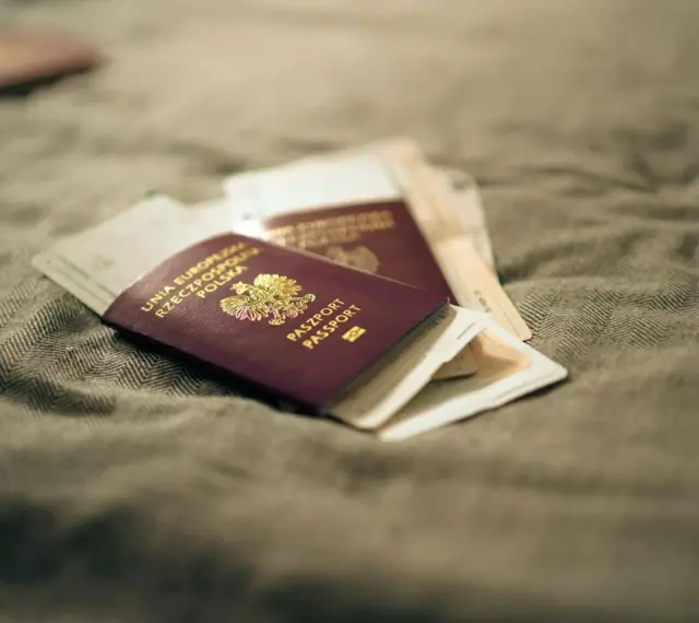 Kilka paszportów leży na szarym materiale. Zastanawiasz się, ile czeka się na paszport w Polsce?