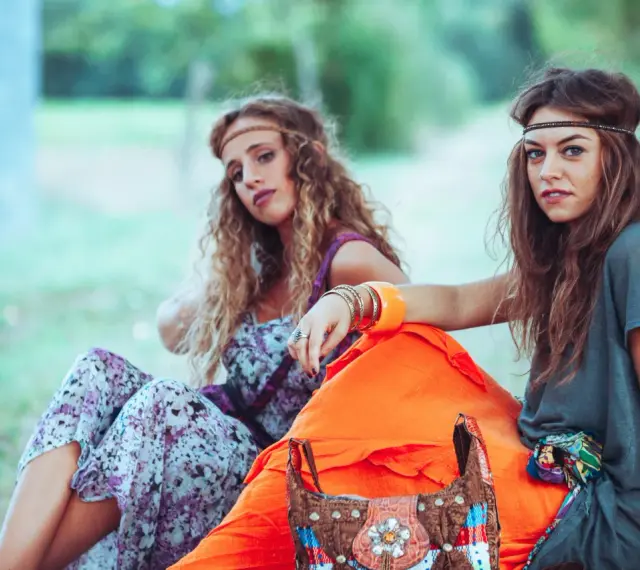 Dwie dziewczyny w stylu boho, idealne inspiracje na imprezę w stylu lat 70 jak się ubrać. Wianki, kwieciste sukienki i kolorowe dodatki.