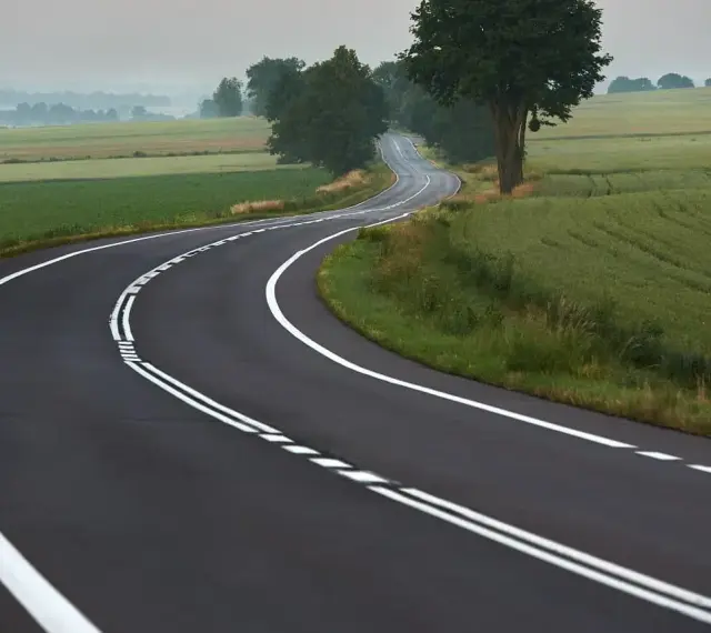 Zakręt drogi z podwójną ciągłą linią. Uważaj, bo wyprzedzanie na podwójnej ciągłej grozi mandatem.