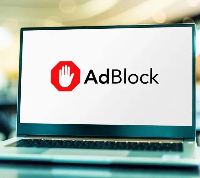 Laptop z logo AdBlock. Dowiedz się, jak wyłączyć adblocka, aby zobaczyć treści.