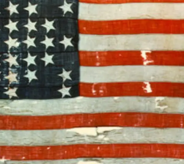Pierwsza flaga USA, zniszczona i wyblakła, z 13 gwiazdami i pasami, świadectwo historii.