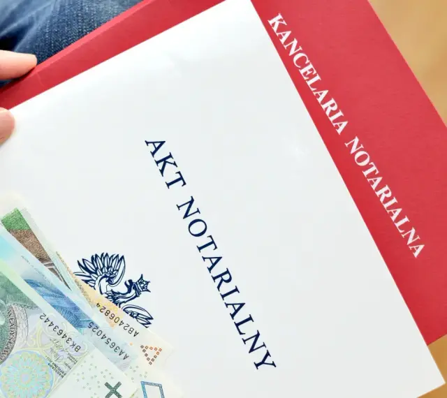 Dłoń trzyma dokument "Akt Notarialny" z Kancelarii Notarialnej, obok leżą polskie banknoty.