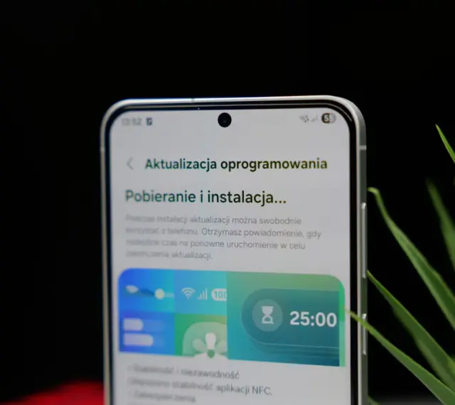 Telefon z interfejsem One UI 8.5 pokazuje ekran pobierania aktualizacji oprogramowania. Widoczny jest zegar 25:00.