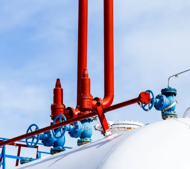 Zawory i rury przy białym zbiorniku na gaz. Zastanawiasz się, na ile wystarcza zbiornik na gaz 2700?