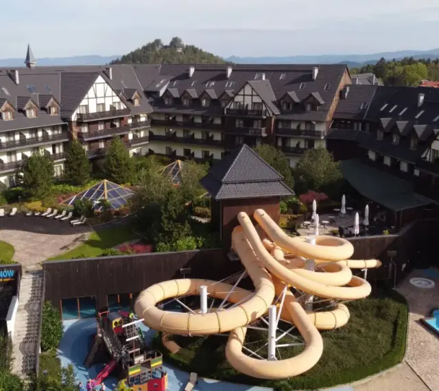 Karpacz hotel z aquaparkiem oferuje zjeżdżalnie i baseny. Widać też góry w tle.