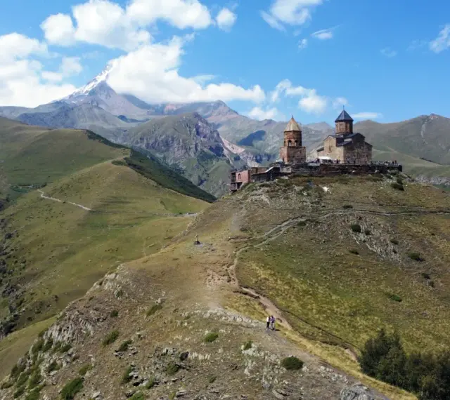 Gruzja wakacje: Kościół Gergeti na tle gór Kaukazu. Widok na malownicze doliny i szczyt Kazbek.
