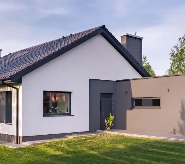 Nowoczesny dom z białymi i grafitowymi akcentami. Elewacja zewnętrzna prezentuje harmonijne połączenie kolorów, tworząc elegancki wygląd.