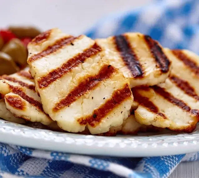 Grillowany ser halloumi na talerzu, z widocznymi paskami z grilla. Idealny dodatek do sałatek, z niską zawartością halloumi kcal.