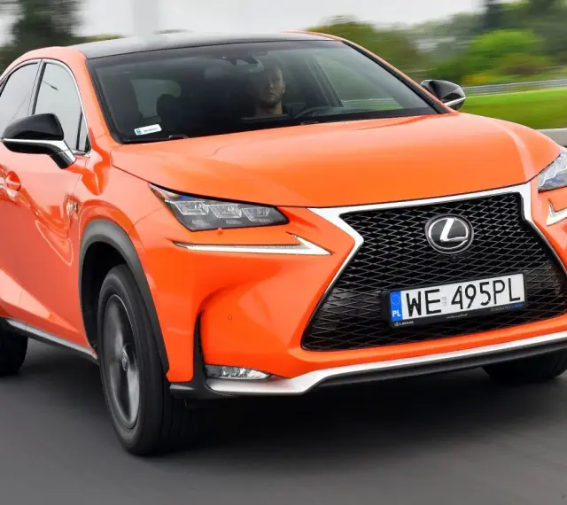 Pomarańczowy Lexus NX 300 jedzie po drodze, kierowca widoczny za kierownicą.