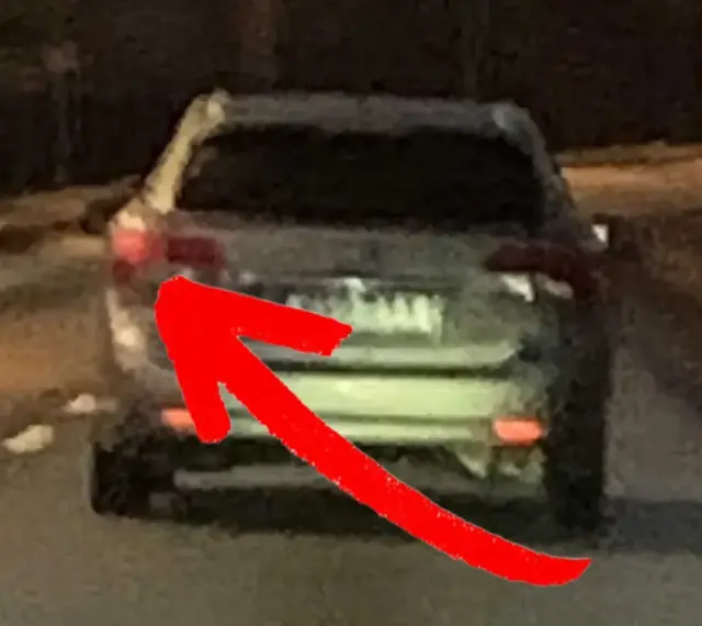 En röd pil pekar på bakljuset på en bil. Det är mörkt ute, och man undrar om man måste ha bakljus på dagen.