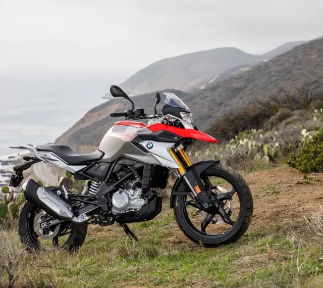 BMW G 310 GS na tle górskiego krajobrazu z widokiem na ocean. Poznaj jego dane techniczne i możliwości terenowe.