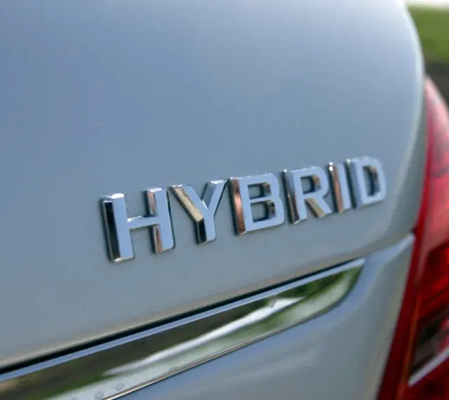 Chromowane napisy "HYBRID" na białym nadwoziu samochodu. To nowoczesny hybrydowy pojazd elektryczny, gotowy na ekologiczną podróż.