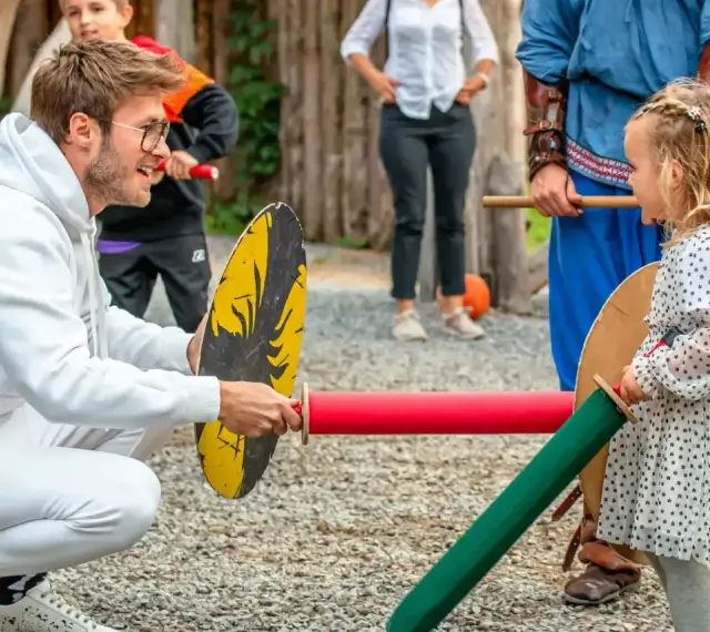 Chłopiec i dziewczynka ćwiczą walkę na miecze. Widać, że dziewczynka ma odwagę i determinację, co są jej mocne strony.