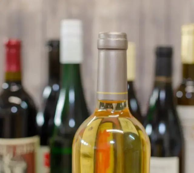 Butelki z winem na tle drewnianej ściany. Zastanawiasz się, ile alkoholu można wziąć do Norwegii samolotem?