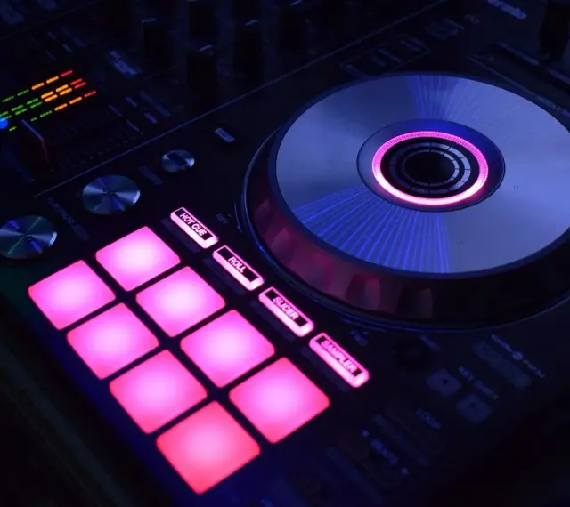 DJ kontroler z podświetlanymi na różowo padami i świecącym na niebiesko talerzem. Idealny do tworzenia muzyki, np. dubstep co to za gatunek?