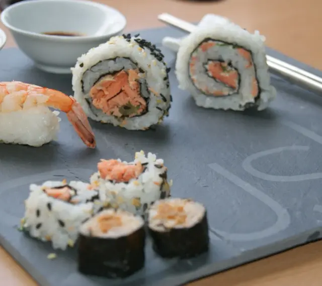 Jak przygotować krewetki do sushi? Na talerzu sushi z krewetką i rolkami z łososiem.