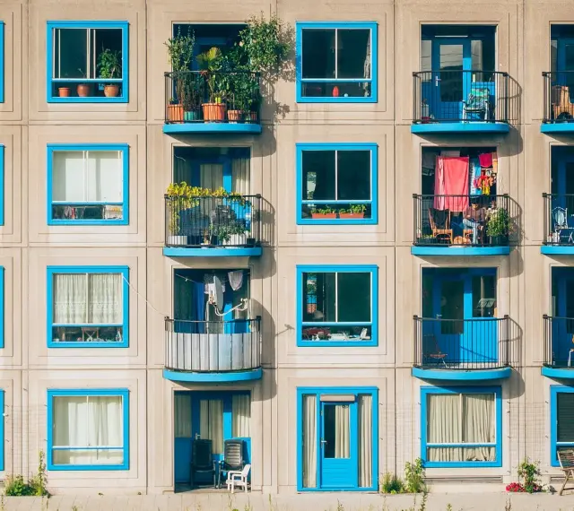 Elegancka loggia i balkon z niebieskimi ramami okiennymi na betonowej fasadzie budynku.