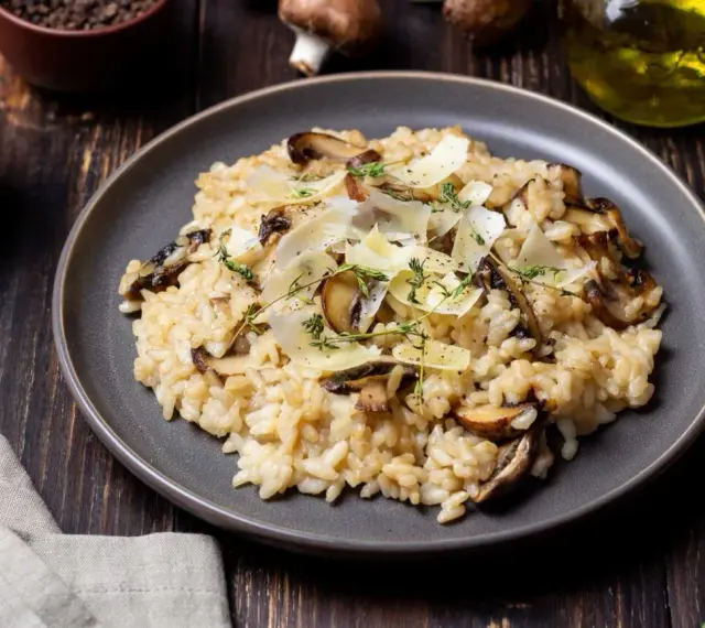 Kremowe risotto z pieczarkami, posypane parmezanem i ziołami.