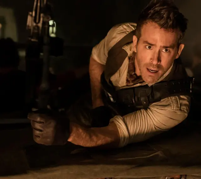 Ryan Reynolds w akcji, jakiego nie widziałeś w jego filmach. Wciela się w rolę bohatera w mrocznym, pełnym napięcia kadrze.
