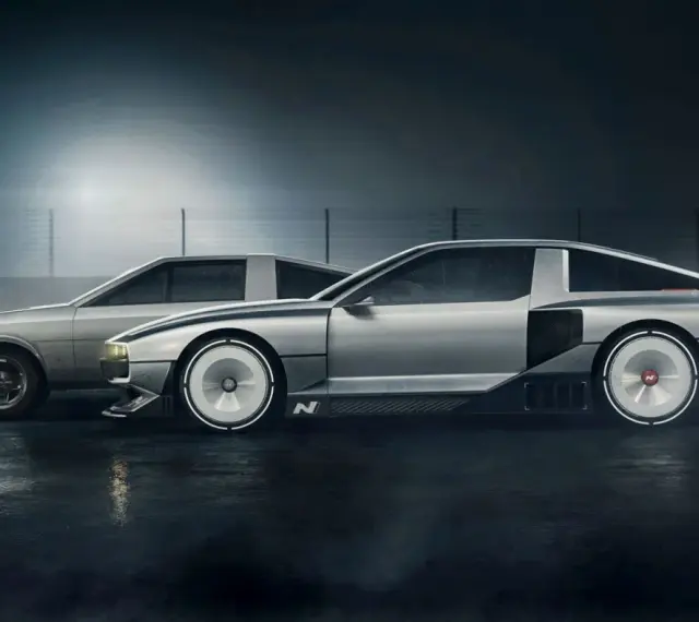 Dwa samochody Hyundai N Vision 74 stoją obok siebie na mokrej nawierzchni. Jeden jest bardziej klasyczny, drugi futurystyczny.