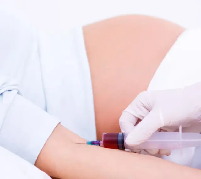 Pobieranie krwi do badań w 15 tygodniu ciąży. Brzuch ciężarnej i ręka z igłą strzykawki.