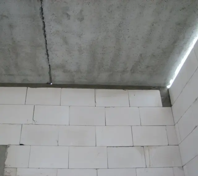Betonowy strop z widocznym pęknięciem nad ścianą z białych pustaków.
