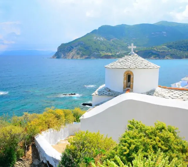 Malownicza zatoka i białe kościółki na wzgórzu. Idealne miejsce na skopelos wakacje.