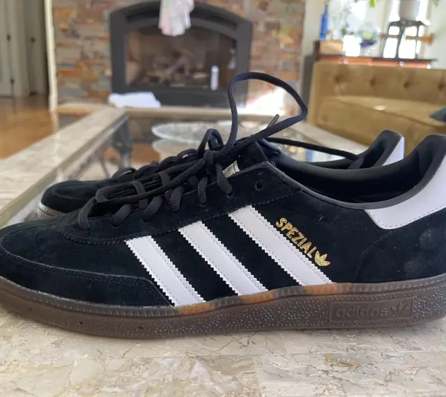 Czarne buty Adidas Spezial z białymi paskami i złotym napisem. Zwróć uwagę na detale, jak rozpoznać oryginalne buty Adidas.