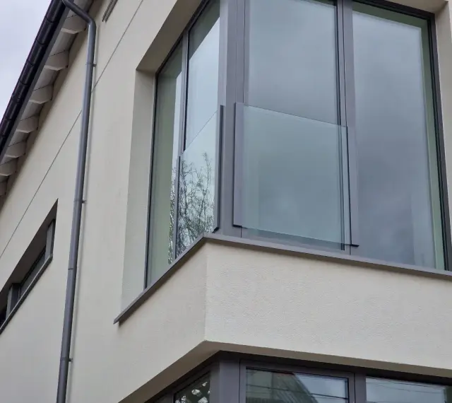Nowoczesne portfenetry z przeszklonymi balustradami na jasnej elewacji.