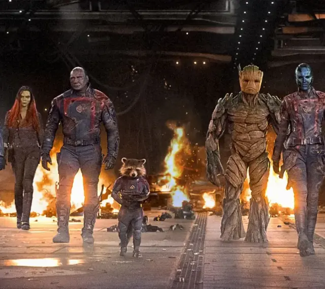 Strażnicy Galaktyki: Volume 3 obsada – Star-Lord, Gamora, Drax, Rocket, Groot, Nebula i Mantis idą przez płonące ruiny.