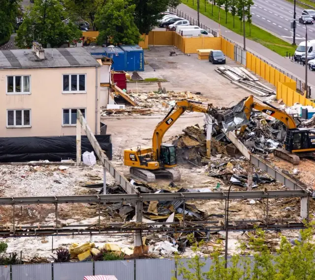 Dwie koparki pracują przy rozbiórce budynku. To przykład zgłoszenia rozbiórki budynku, gdzie widać postęp prac.