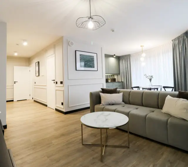 Nowoczesny apartament suite, z wygodną kanapą, stolikiem kawowym i widokiem na kuchnię.