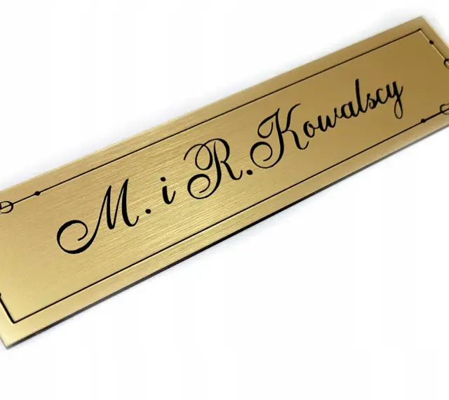 Elegancki, złoty szyld z napisem "M. i R. Kowalscy" w ozdobnej ramce.
