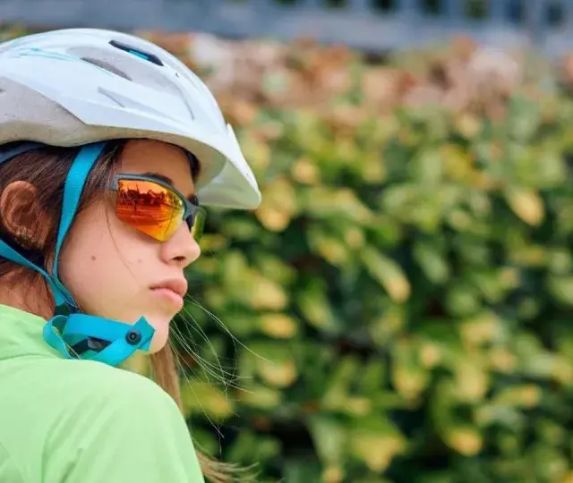 Młoda rowerzystka w kasku i okularach przeciwsłonecznych. Czy kask na rower jest obowiązkowy? Bezpieczeństwo przede wszystkim!