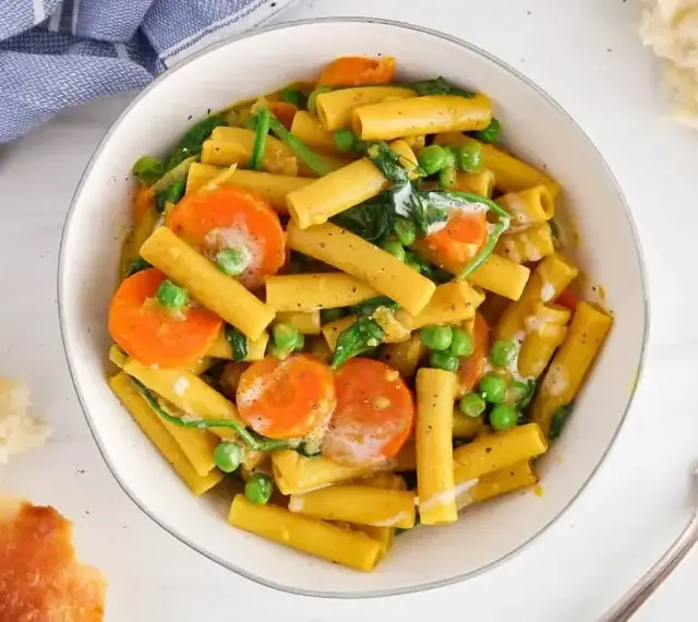 Makaron z mlekiem kokosowym i curry, z marchewką i groszkiem. Kremowy sos otula złociste rurki, tworząc aromatyczne danie.
