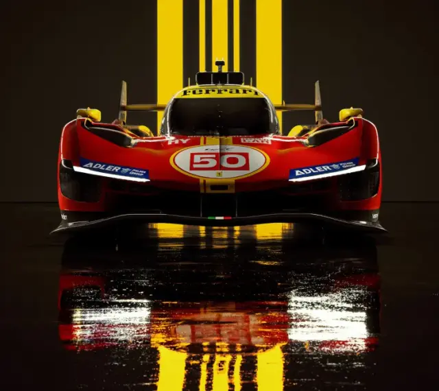 Wyścigowy Ferrari 499P w czerwono-żółtych barwach, z numerem 50, odbija się w mokrej nawierzchni.
