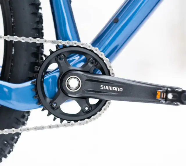 Jak odkręcić pedały w rowerze? Widok na korbę Shimano, łańcuch i fragment ramy roweru.