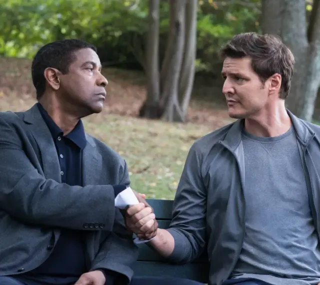 Denzel Washington i Pedro Pascal, obsada "Bez litości 2", siedzą na ławce i ściskają sobie dłonie.