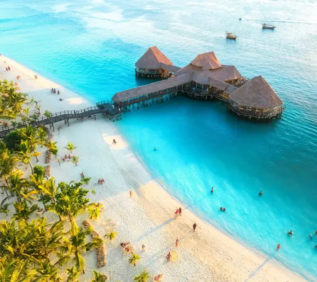 Rajska plaża na Zanzibarze z palmami i restauracją na wodzie. Sprawdź Zanzibar ceny, by zaplanować wymarzone wakacje.