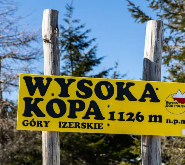 Żółta tablica informuje o szczycie Wysoka Kopa, najwyższym szczycie Gór Izerskich, na wysokości 1126 m n.p.m.