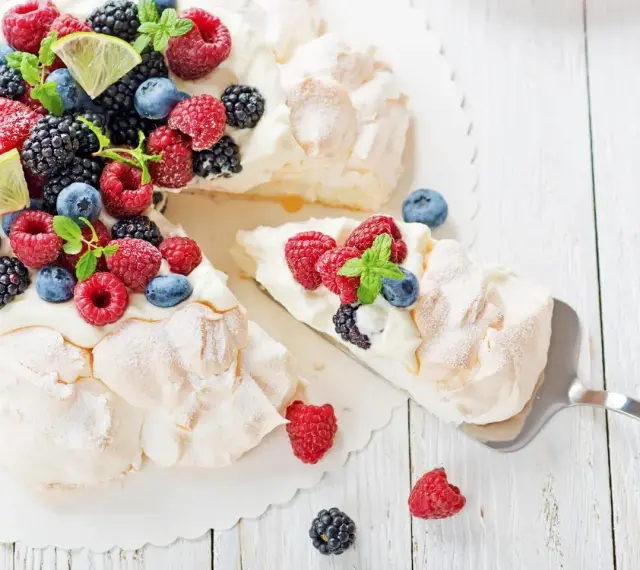Beza pavlova która zawsze wychodzi, udekorowana świeżymi malinami, borówkami, jeżynami i plasterkami limonki.