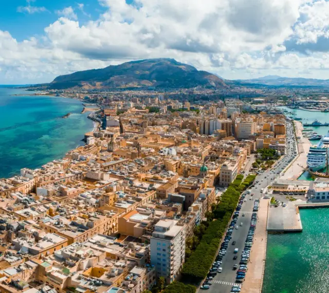 Widok na Trapani, Sycylia. Miasto z widokiem na turkusowe morze i góry. Zobacz, co warto zobaczyć w Trapani: port z luksusowym rejsem i zabytkowymi żaglowcami.
