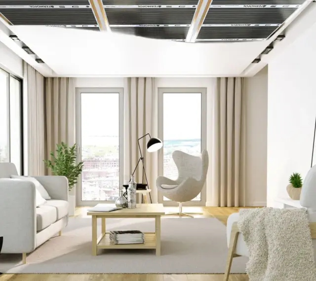 Nowoczesny salon z ogrzewaniem sufitowym. Jasne meble, duże okna i dyskretne panele grzewcze tworzą przytulną atmosferę.