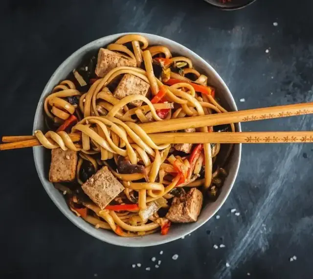 Miseczka z makaronem udon, tofu i warzywami, gotowa do podania. Idealny przepis na pad udon.