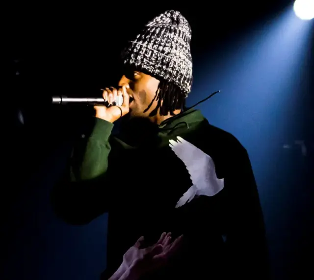 Playboi Carti Polska na scenie, w czapce i bluzie z gołębiem.